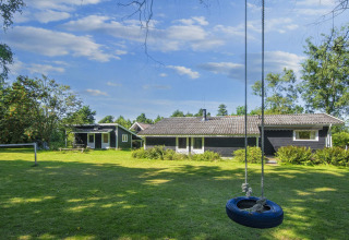 Photo of "6 person holiday home in Glesborg" in Denmark with large lawn, tire swing, and wooden house.