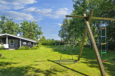 Playground with swing and ladder at 6 person holiday home in Glesborg, Denmark, surrounded by trees.
