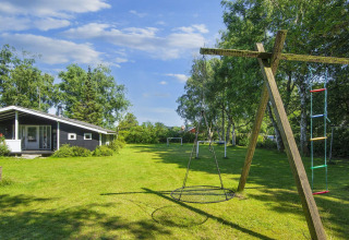 Playground with swing and ladder at 6 person holiday home in Glesborg, Denmark, surrounded by trees.