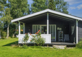 Acogedora casa de vacaciones en Glesborg, Dinamarca, con terraza y jardín rodeada de naturaleza verde.