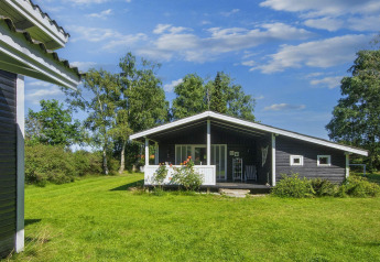 Imagen de una casa de vacaciones para 6 personas en Glesborg rodeada de césped y árboles verdes.