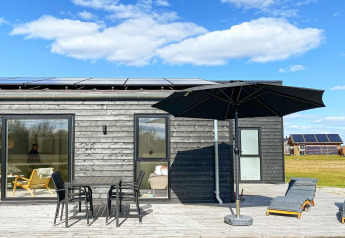 Terrazza della 'Casa vacanze per 8 persone ad Ansager', Danimarca, con mobili e ombrellone da esterno.