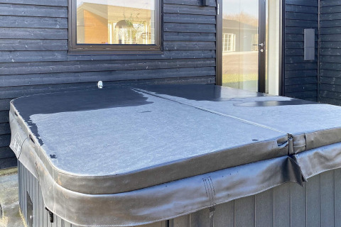 Udendørs boblebad med sort låg foran et sort træhus ved 8 personers feriehus i Ansager, Danmark.