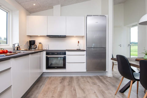 Moderne keuken met witte kasten, grote koelkast en eetruimte in 8-persoons vakantiehuis in Ansager, Denemarken.