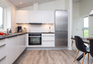 Moderne keuken met witte kasten, grote koelkast en eetruimte in 8-persoons vakantiehuis in Ansager, Denemarken.
