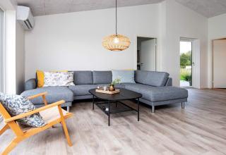 Salon moderne dans maison de vacances 8 personnes à Ansager, Danemark, avec canapé gris et lumière chaleureuse.