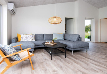 Salon moderne dans maison de vacances 8 personnes à Ansager, Danemark, avec canapé gris et lumière chaleureuse.
