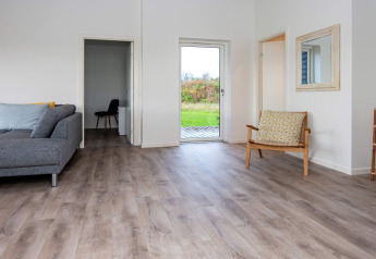 Moderne leefruimte in vakantiehuis met houten vloer en zicht op tuin in Ansager, Denemarken.