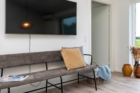 Moderne opholdsstue på et feriehus i Ansager, Danmark med bænk, TV og dekorative krukker.