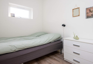 Moderne og minimalistisk soveværelse i 8 personers feriebolig i Ansager, Danmark med enkel seng og kommode.