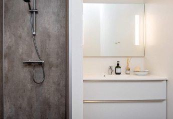 Moderne badkamer met douche, verlichte spiegel en witte wastafel in een 8-persoons vakantiehuis in Ansager.