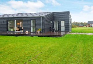 Lodge de vacances moderne noire à Ansager, Danemark, avec terrasse spacieuse et pelouse verdoyante