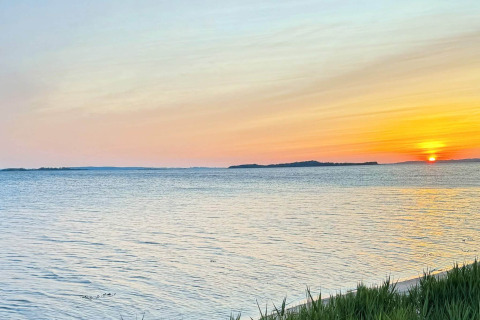 Zonsondergang boven zee vanaf het 12-persoons vakantiehuis in Millinge, Denemarken, met zachte tinten.