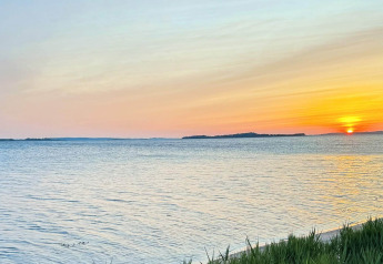 Zonsondergang boven zee vanaf het 12-persoons vakantiehuis in Millinge, Denemarken, met zachte tinten.