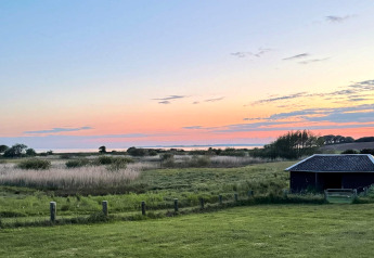 Coucher de soleil vu du gîte de 12 personnes à Millinge, Danemark, avec prairie et petite grange.