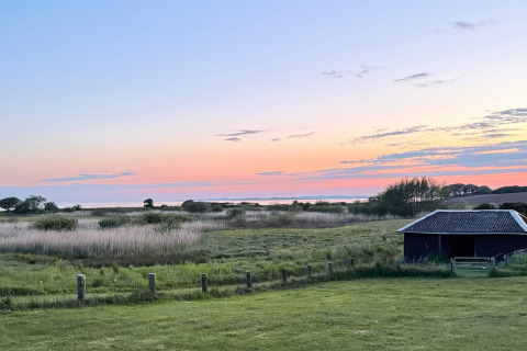Zonsondergang bij 12-persoons vakantiehuis in Millinge, Denemarken, met velden en een schuurtje.