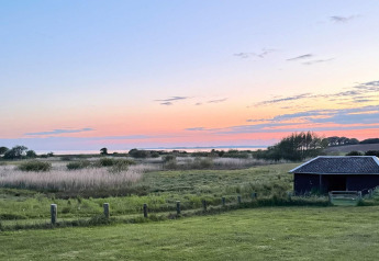 Zonsondergang bij 12-persoons vakantiehuis in Millinge, Denemarken, met velden en een schuurtje.