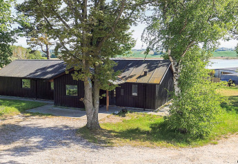 Foto van 12-persoons vakantiehuis in Millinge, Denemarken, omgeven door bomen en nabij het water.