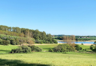 Paesaggio verde con lago e cielo azzurro visto dalla casa vacanze per 12 persone a Millinge, Danimarca.