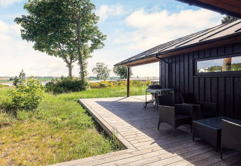 Terrasse en bois avec mobilier extérieur et barbecue au gîte pour 12 personnes à Millinge, Danemark, vue nature.