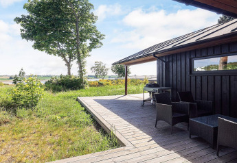 Houten terras met tuinmeubilair en barbecue bij 12-persoons vakantiehuis in Millinge, Denemarken, met uitzicht.