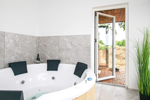 Bain à remous avec quatre appuis-tête, bouteille de champagne et porte ouverte dans une maison à Millinge, Danemark.