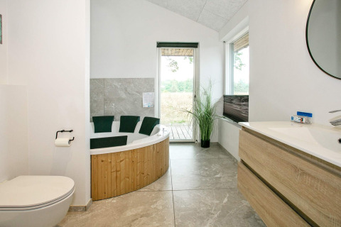 Bagno moderno con vasca idromassaggio, wc e mobile in legno in una casa vacanze a Millinge, Danimarca.