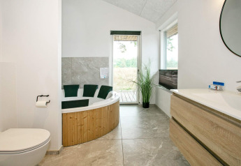 Moderne badkamer met bubbelbad, toilet en houten wastafel in een vakantiehuis in Millinge, Denemarken.