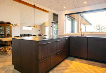 Cuisine moderne dans une maison de vacances à Millinge, Danemark, avec armoires foncées et grandes fenêtres.