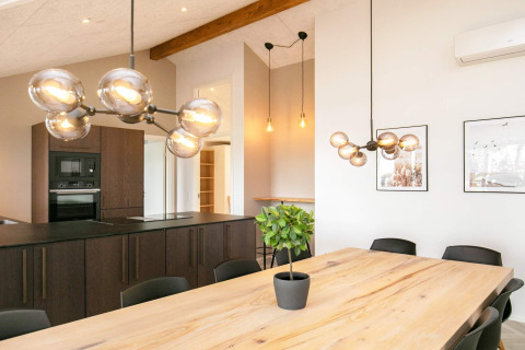 Moderne eet- en keukenruimte in 12-persoons vakantiehuis in Millinge, Denemarken, met houten tafel en lampen.