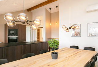 Zona pranzo e cucina moderna in casa vacanze per 12 persone a Millinge, Danimarca, con tavolo in legno.