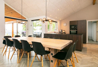 Moderne eet- en keukenruimte in een 12-persoons vakantiehuis in Millinge, Denemarken, met grote ramen.