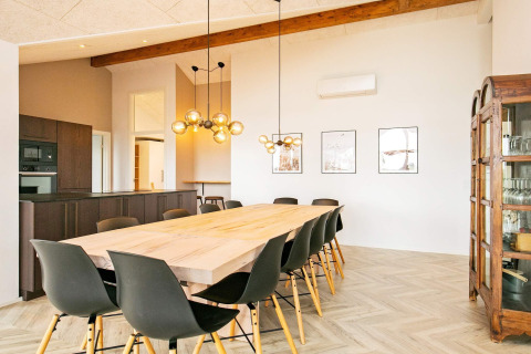 Moderne spisestue i feriebolig i Millinge, Danmark, med langt træbord, sorte stole og loftsbelysning.