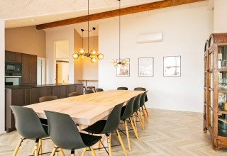 Comedor moderno en casa de vacaciones en Millinge, Dinamarca, con mesa larga de madera y sillas negras.