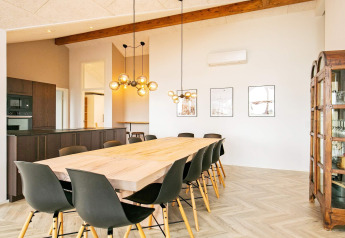 Moderne eetkamer in vakantiehuis in Millinge, Denemarken, met lange houten tafel en zwarte stoelen.