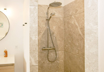 Moderne douche met regendouchekop en beige marmeren tegels in 12-persoons vakantiehuis in Millinge, Denemarken.