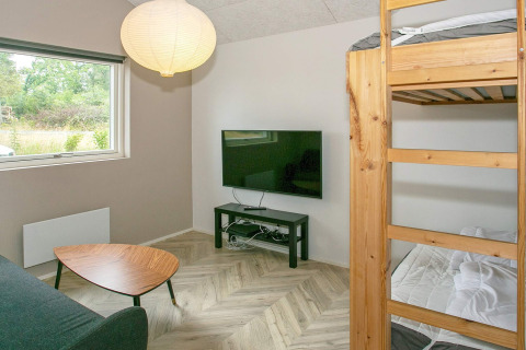 Salón con litera, mesa de centro, televisor de pantalla plana y vista a la naturaleza en casa de Millinge.