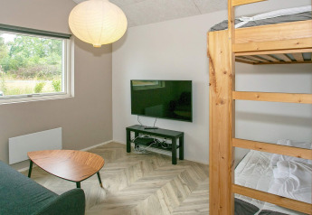 Woonkamer met stapelbed, salontafel, flatscreen-tv en natuurzicht in 12-persoons vakantiehuis in Millinge.