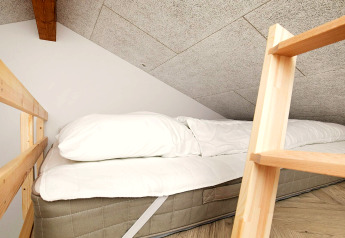 Espace nuit confortable avec matelas sous plafond en pente, dans une maison de vacances à Millinge, Danemark.
