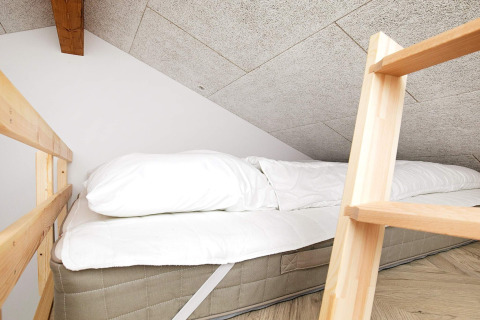 Espace nuit confortable avec matelas sous plafond en pente, dans une maison de vacances à Millinge, Danemark.