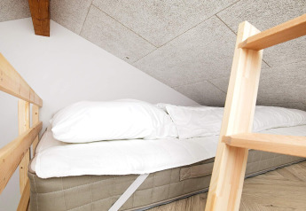 Knusse slaapruimte met matras en kussen onder schuin plafond in een vakantiehuis in Millinge, Denemarken.