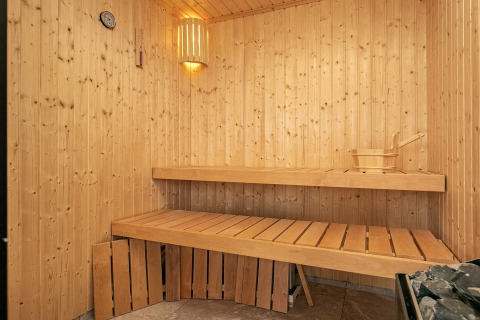 Sauna interna in legno nella casa vacanze per 12 persone a Millinge, Danimarca, con panche e stufa.
