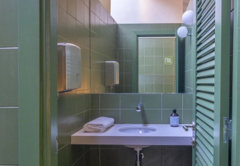 Modern bathroom with green tiles, sink, mirror, skylight in a Bell Tent at Wecamp Cala Montgó, Spain.