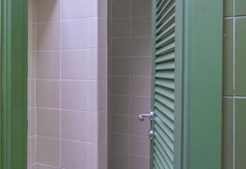 Bathroom inside Bell Tent at Wecamp Cala Montgó, Spain, showing green door and beige tiles.