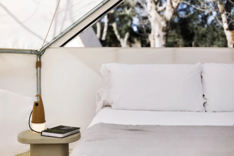 Vista interna della Bell Tent Plus al Wecamp Cala Montgó in Spagna con letto e comodino.