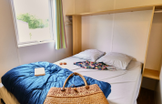Schlafzimmer im Bungalowzelt bei Ludo Camping, Frankreich, mit Doppelbett, Fenster und Tasche.