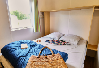 Camera da letto in Bungalowtent presso Ludo Camping, Francia, con letto matrimoniale e finestra.