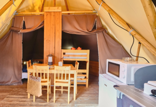 Binnen in een Tipi Tent bij Ludo Camping in Frankrijk, met eettafel, microgolfoven en stapelbedden.