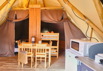 Innenansicht eines Tipi-Zeltes bei Ludo Camping, Frankreich, mit Esstisch, Mikrowelle und Etagenbett.