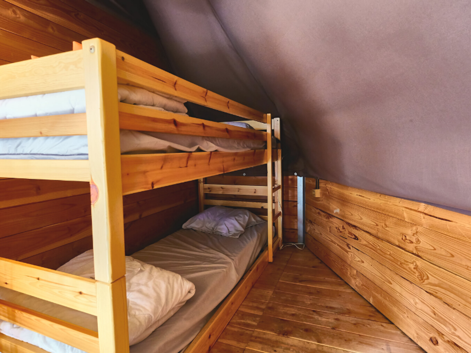 Binnenzicht van de Tipi Tent bij Ludo Camping in Frankrijk met houten vloer en stapelbedden.